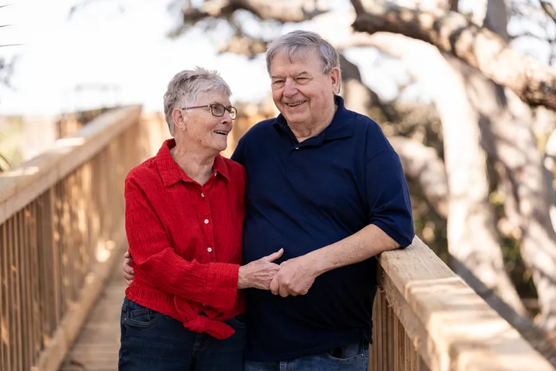 Grandparents smiling at each other on the wooden boardwalk at Nease Park