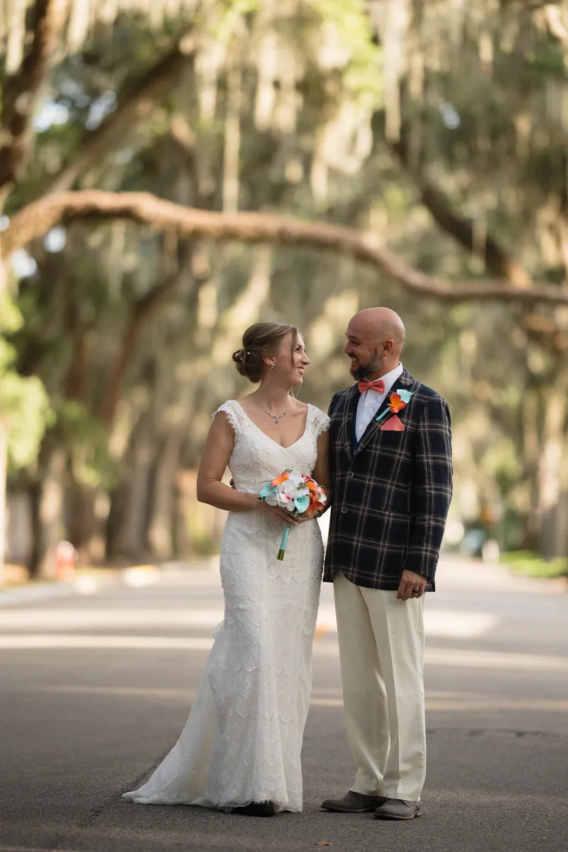 Couple standing together under Spanish moss-draped oaks