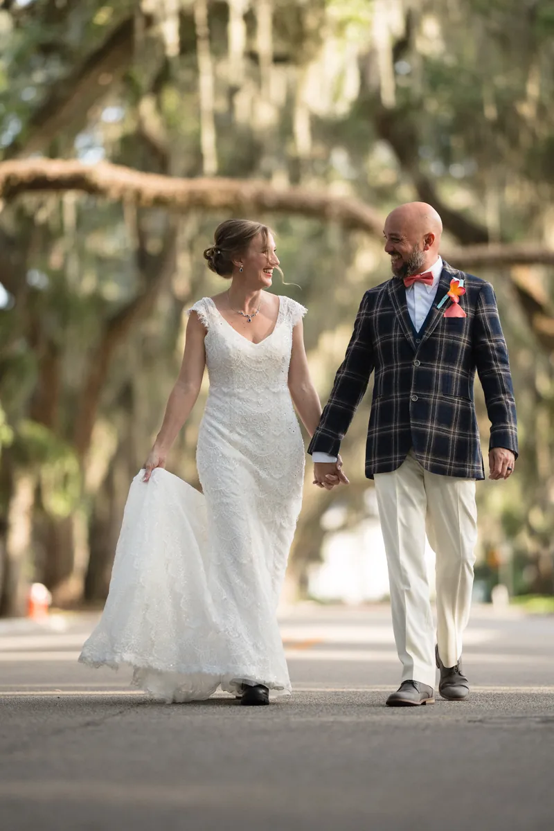 Couple walking hand in hand under oak canopy