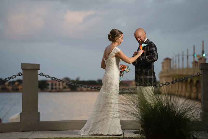Bride adjusting groom's boutonniere on bayfront