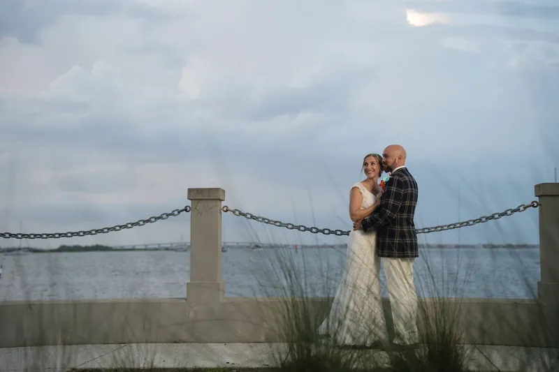 Couple embracing on bayfront with grassy backdrop