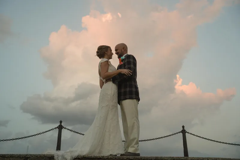 Couple silhouetted against sunset sky on bayfront seawall