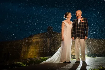Couple in rain with Castillo de San Marcos lit up behind them