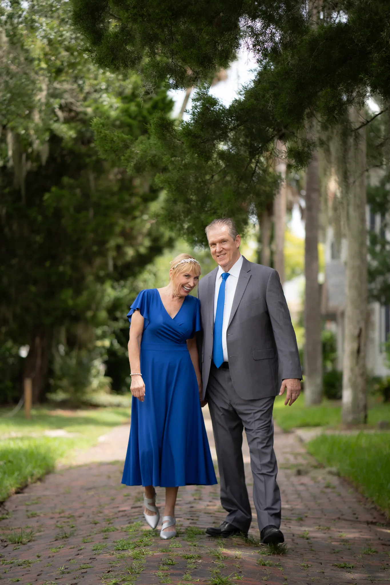 Marlene and Keith walking together on brick path under oak trees St. Augustine