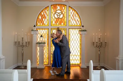 Marlene and Keith first kiss at Amore Wedding Chapel with stained glass backdrop