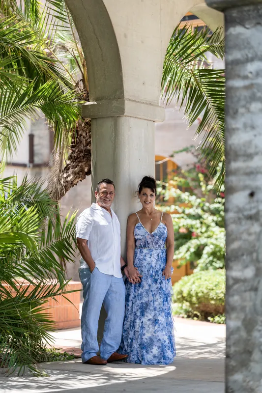 Brian and Mary stand together under a covered pavilion framed by palm trees at the museum courtyard.