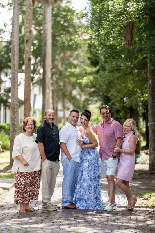 Mary and Brian stand with family members on a tree-lined path, Mary in her blue floral dress.