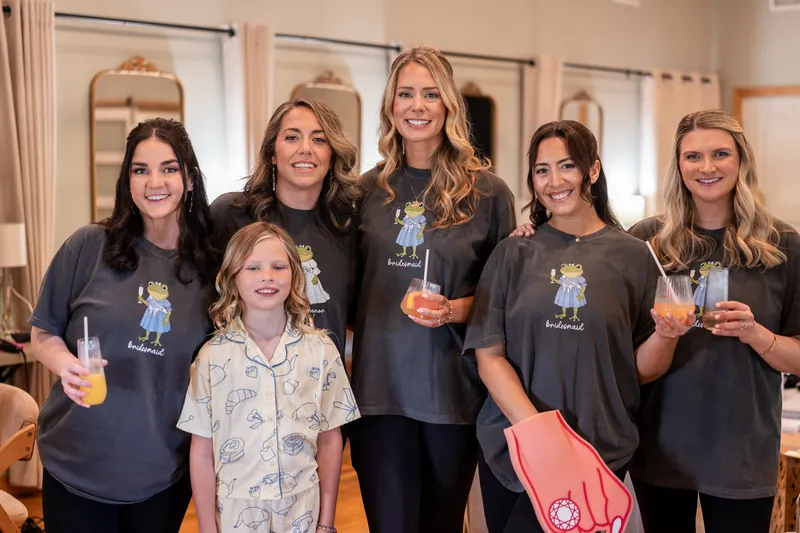 Bridal party in Princess and the Frog themed getting ready shirts holding drinks