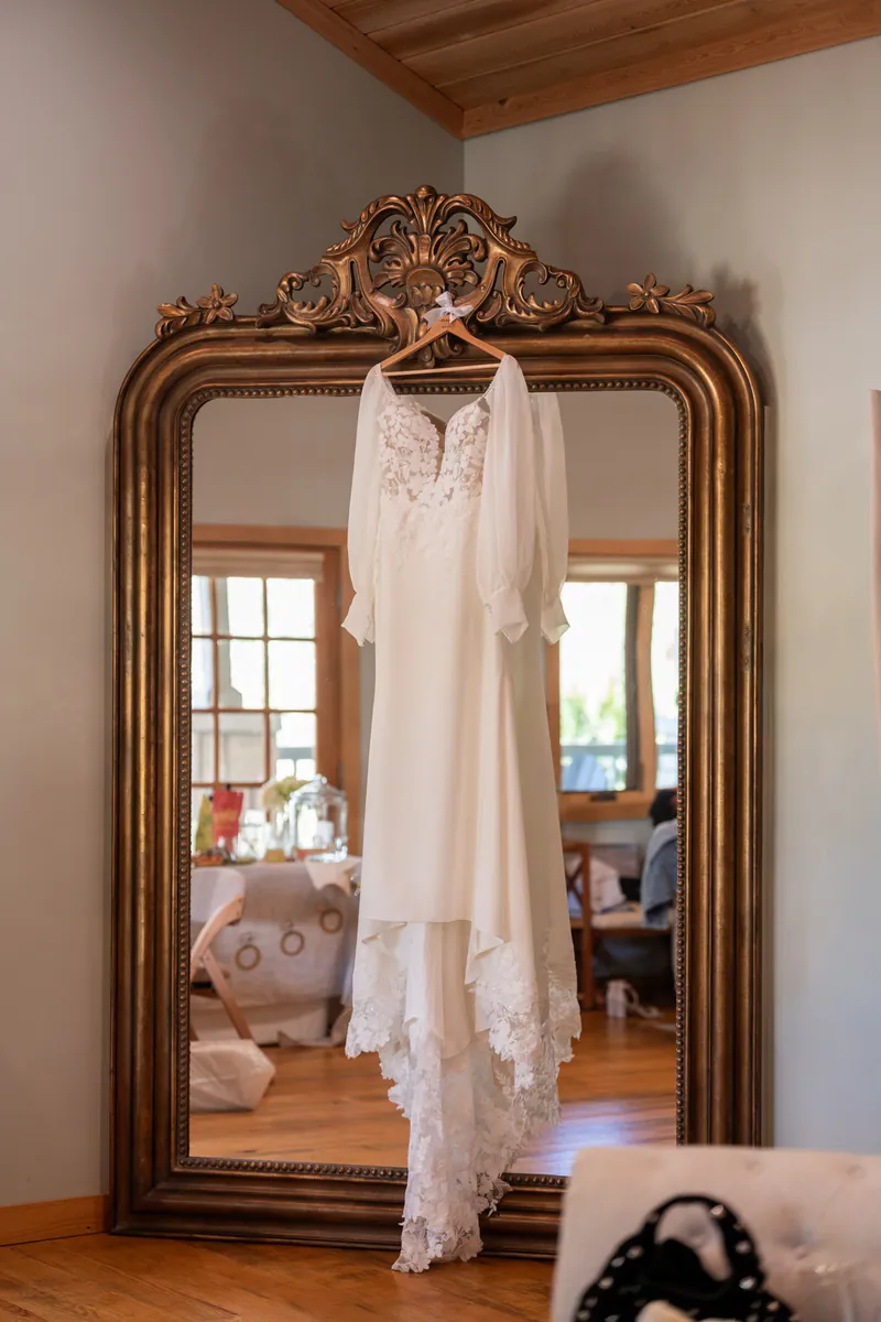Wedding dress hanging on ornate gold mirror