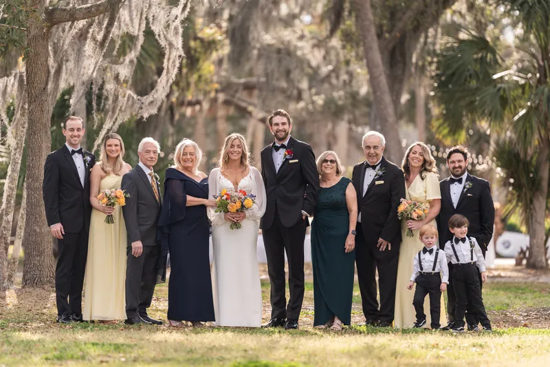 Groom crouching with three ring bearer boys, one wearing sunglasses