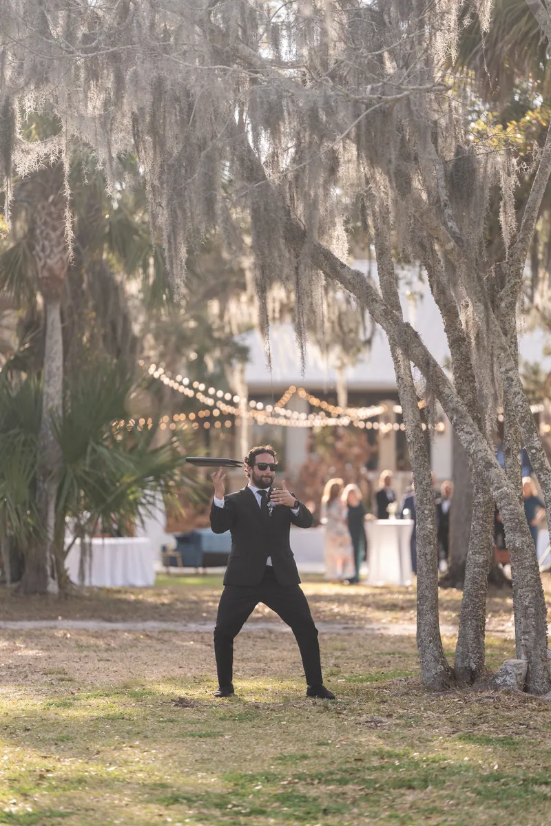 Groom celebrating under Spanish moss with string lights behind him