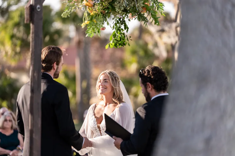 Bride smiling at groom during vows with officiant beside them