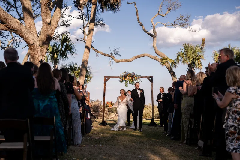 Couple walking back up the aisle as guests stand and cheer after ceremony