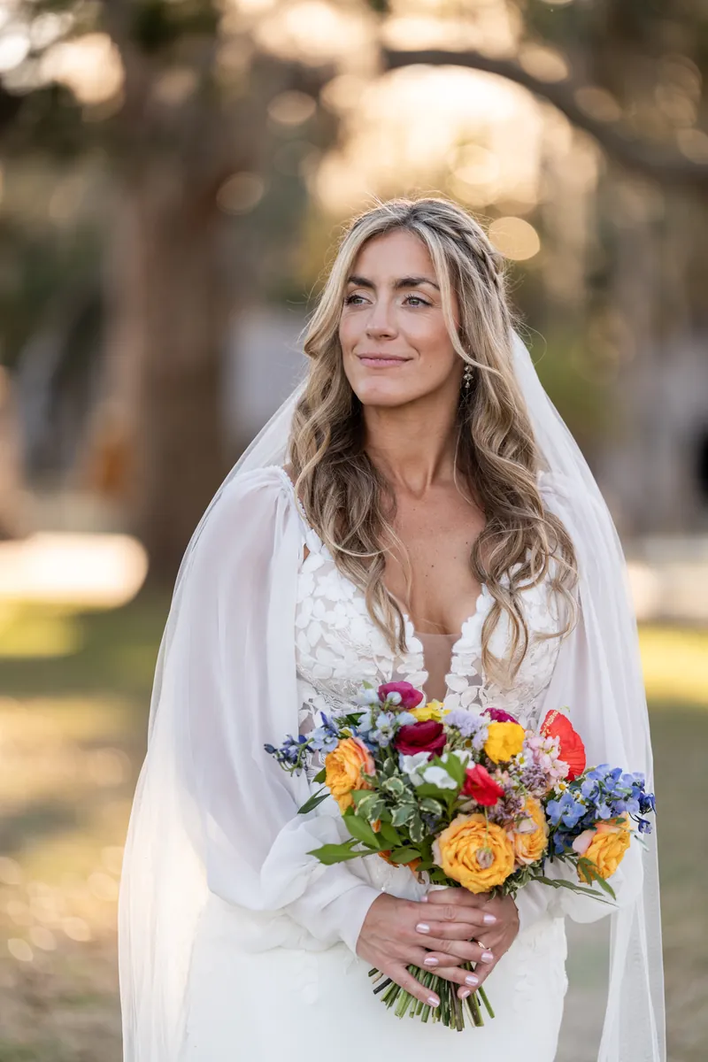 Bridal portrait with veil and colorful bouquet in golden hour light