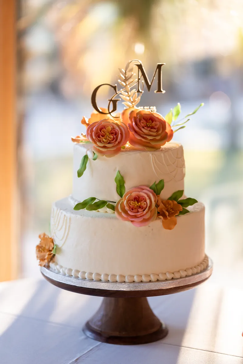 Three-tier wedding cake with sugar flowers and gold G and M topper