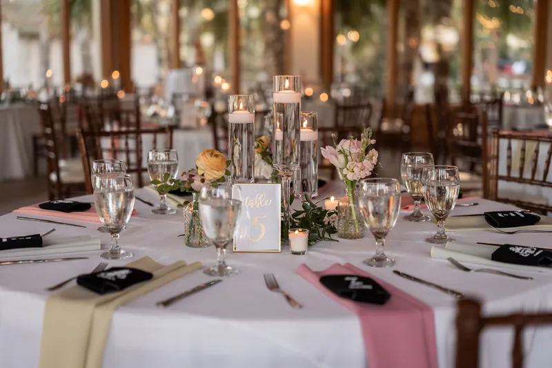 Full table setting with pink and yellow napkins, floating candles, and chiavari chairs