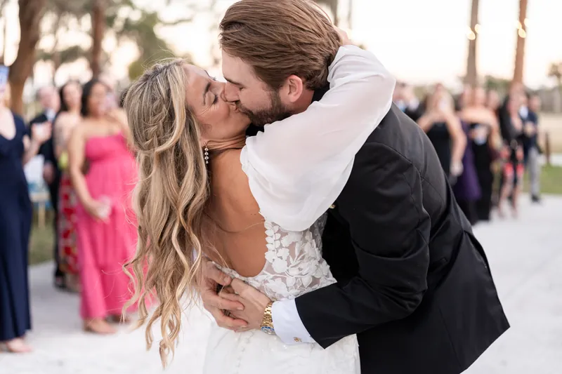 Couple kissing during grand entrance as guests surround them