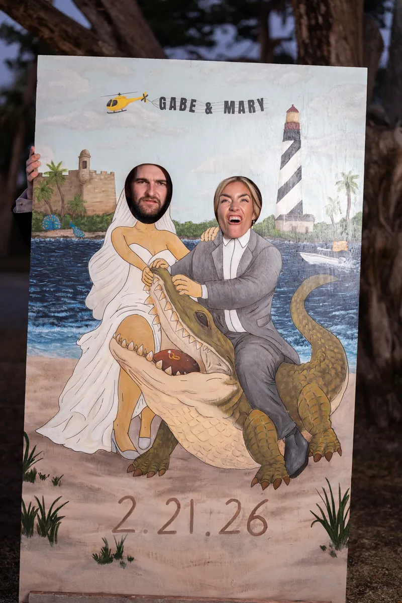 Bride and groom swapping sides on custom photo cutout and laughing