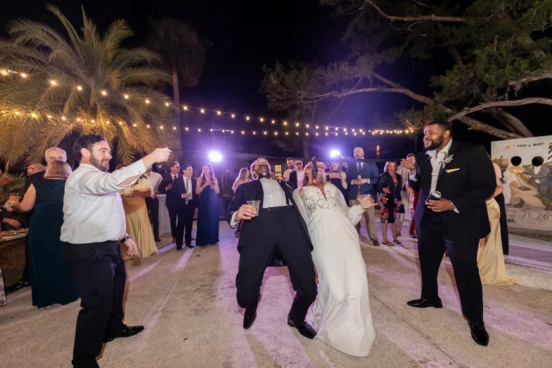 Father and bride low dip on dance floor with guests cheering around them
