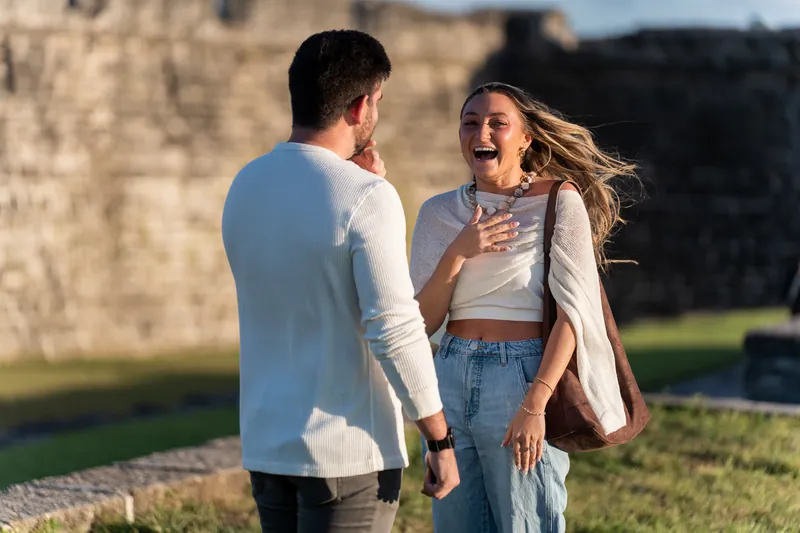 Matt and Mary face each other at Castillo de San Marcos, both laughing as she touches her chest in surprise.