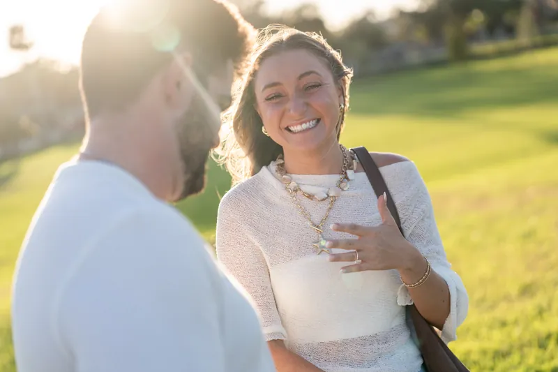 Two people stand close together at Castillo de San Marcos, the person on the right grinning widely while glancing down at their hand.