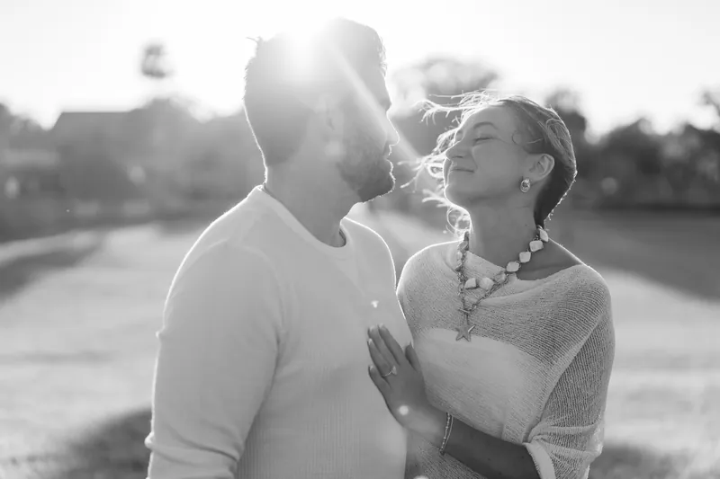 Black-and-white portrait of the couple embracing and gazing at each other as golden light floods the scene at the historic site.