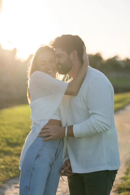 Embracing at dusk, two people share a moment in front of the glowing stone walls of the historic fort.