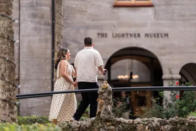 Couple standing by stone wall at Lightner Museum entrance