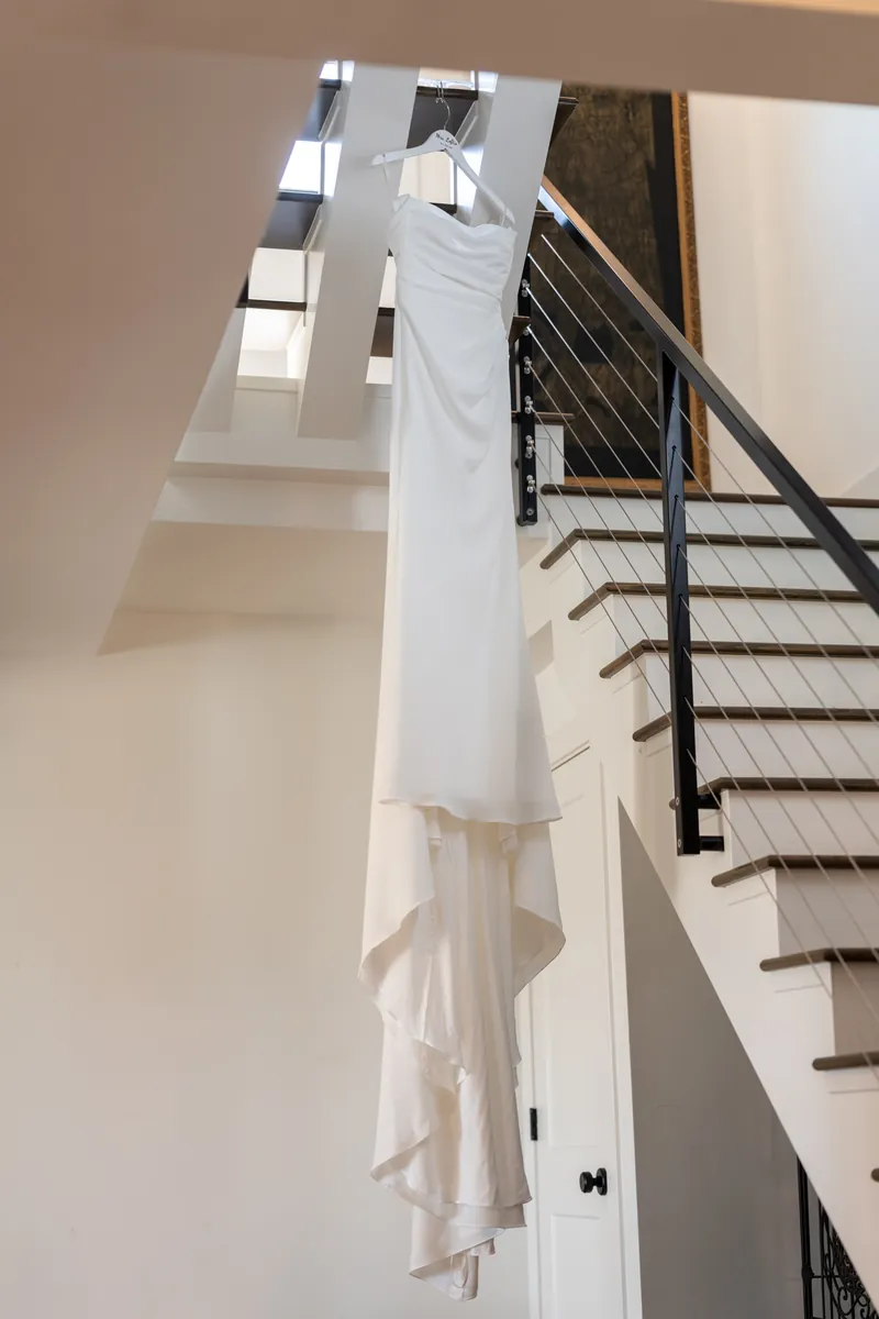 Bride standing on staircase in white ruffle top before getting dressed