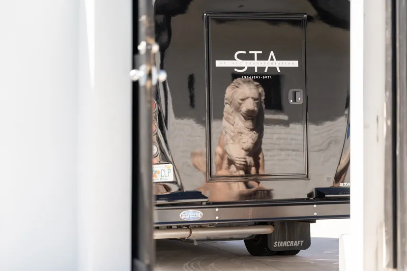 Black STA Transportation party bus reflecting a stone lion statue