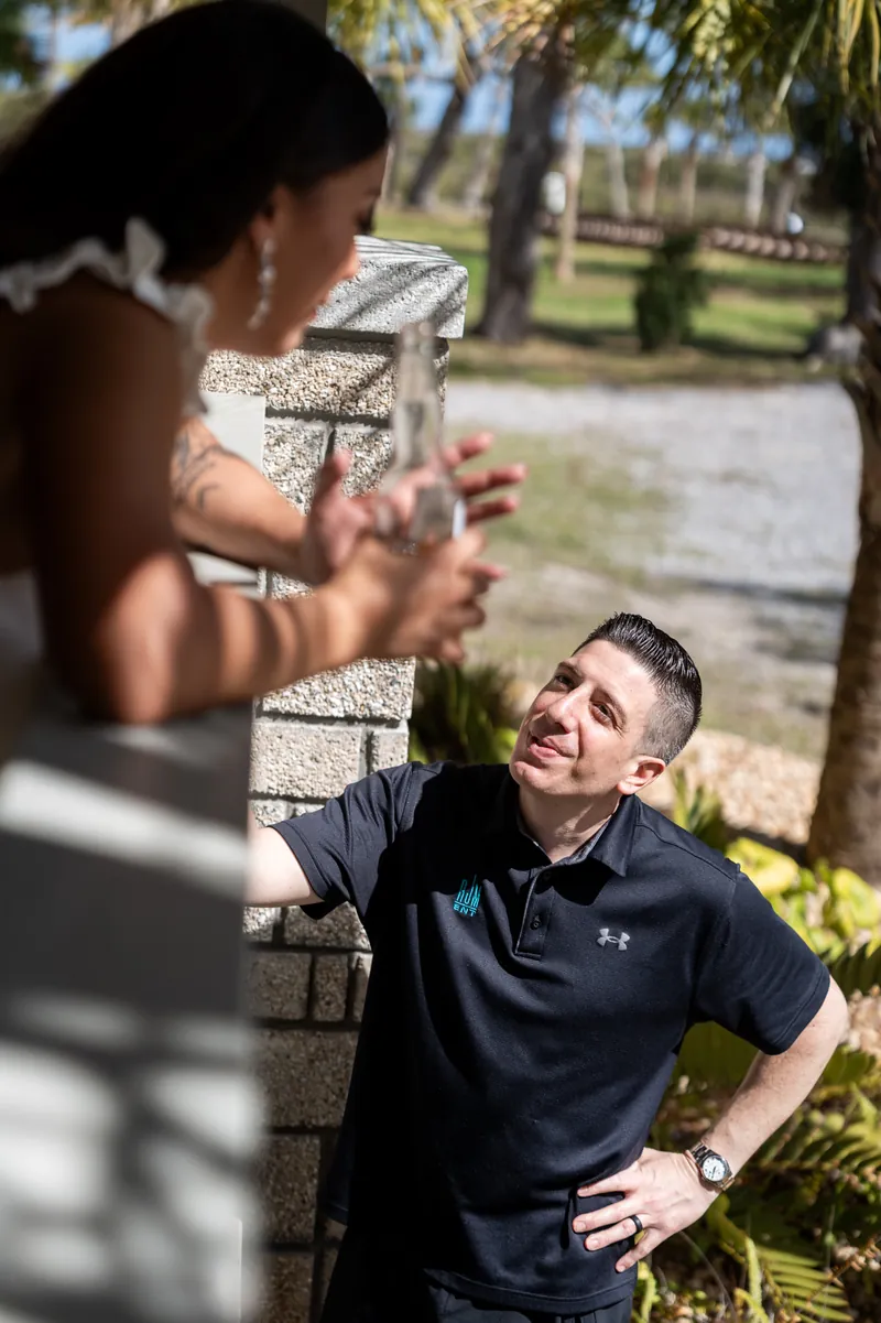 Bride holding her tropical bouquet next to a full length mirror with wedding dress hanging behind her
