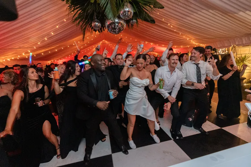 Couple dancing together on the black and white dance floor surrounded by guests