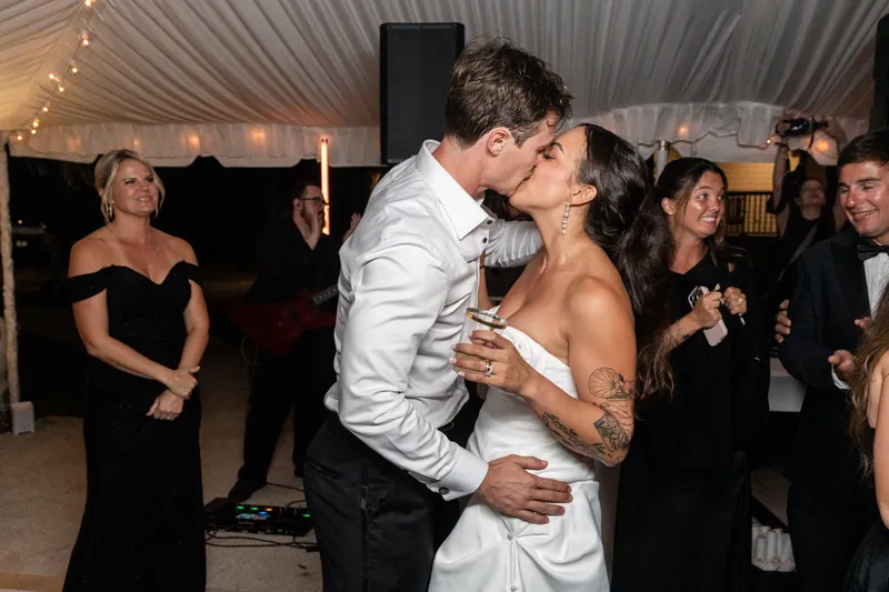 Couple kissing on the dance floor with guests watching and cheering
