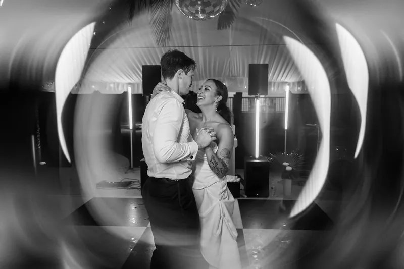 Black and white light trail portrait of couple dancing together at end of reception
