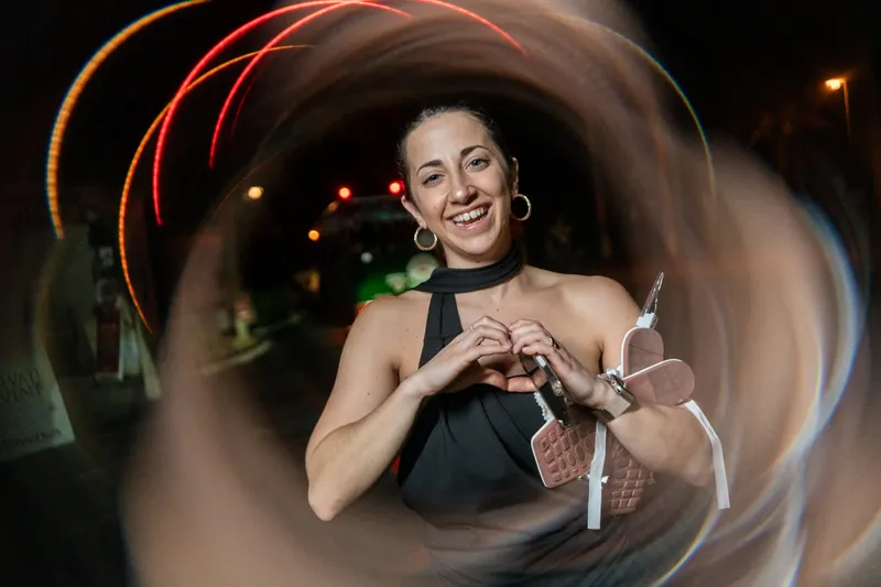Guest making heart shape with hands with light trail effect at night