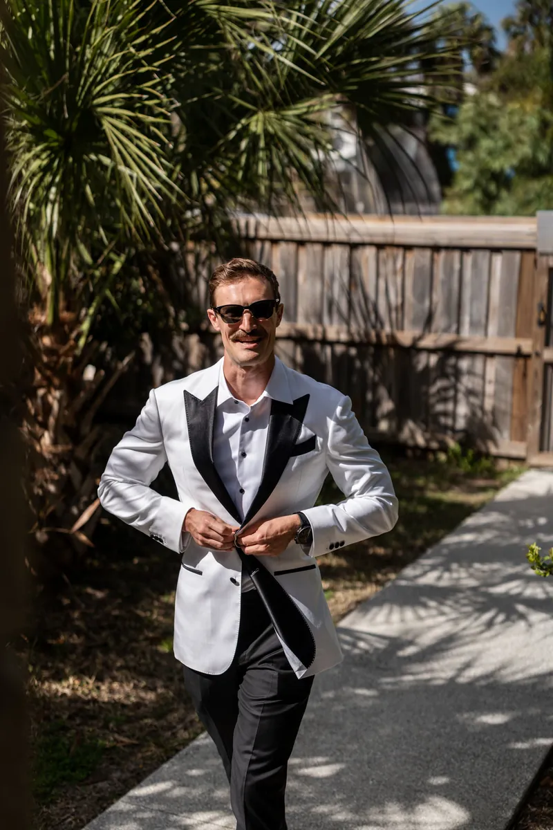 Bride detail shot of white lace pointed-toe heels and off-shoulder wedding dress