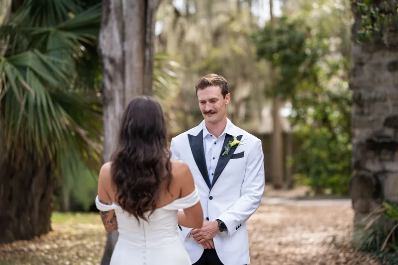 Bryant looking at Michelle during first look with palm trees and Spanish moss behind them