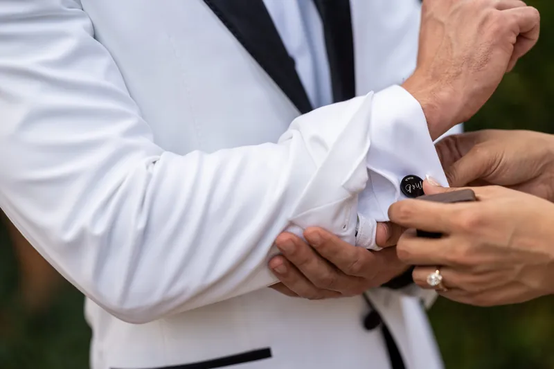 Close-up of custom cufflinks on grooms white tuxedo shirt sleeve
