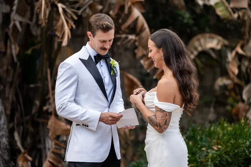 Couple reading private vows and laughing together among the garden paths