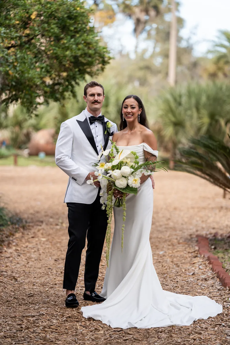 Bride and groom standing together on garden path holding tropical bouquet at Fountain of Youth