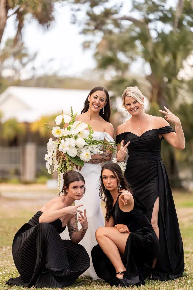 Bride with three close bridesmaids posing playfully with peace signs and bouquet