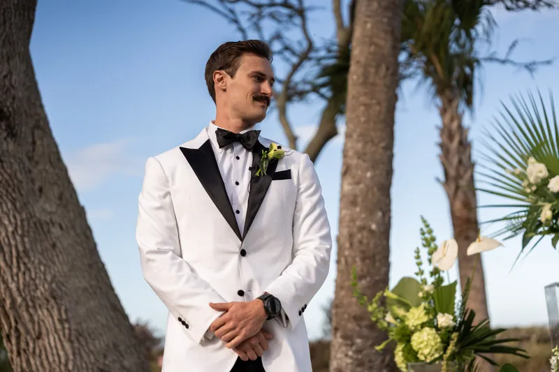 Groom waiting at the altar with palm trees and tropical floral arrangements