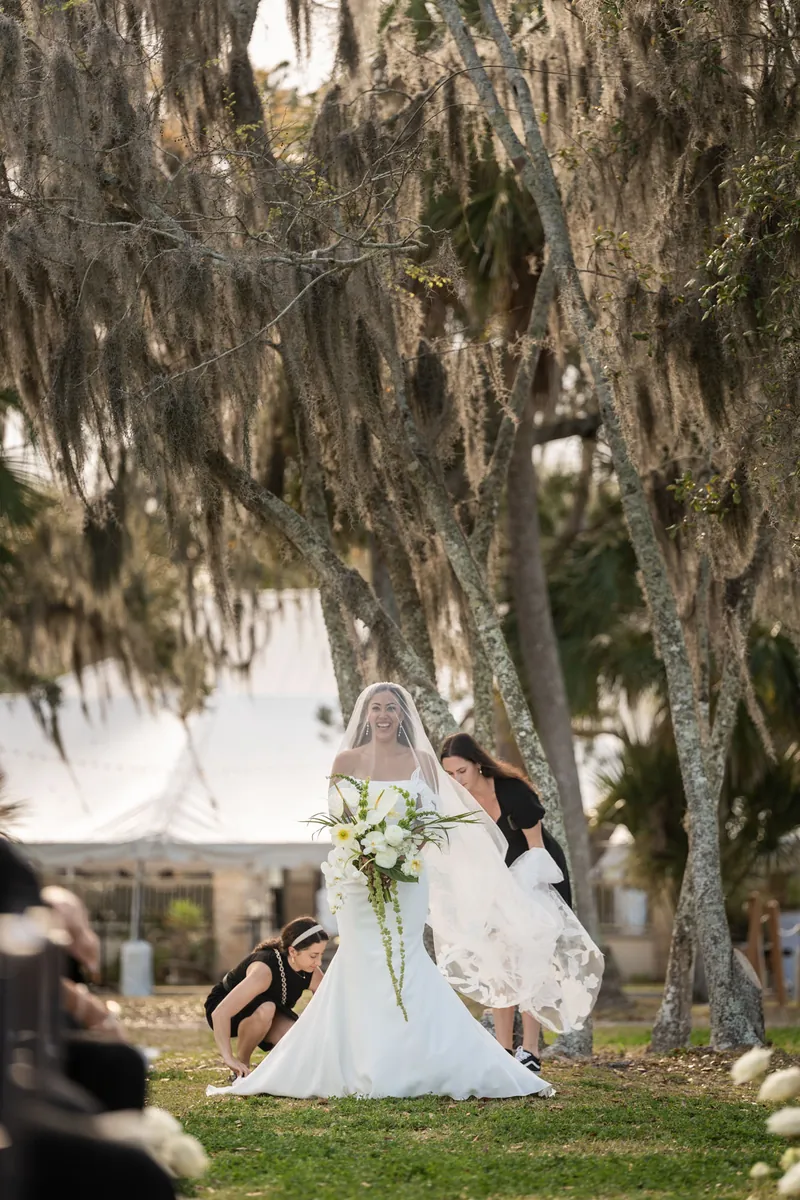 Bride walking down the aisle with her father under Spanish moss draped oak trees