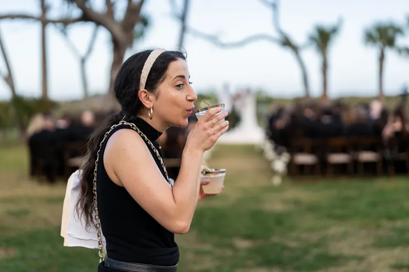 Coordinator sipping a drink while watching the ceremony from the side