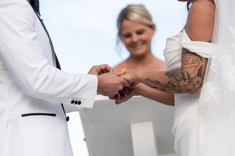 Close-up of ring exchange with officiant smiling in background
