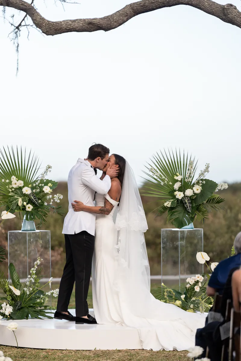 First kiss at the altar with tropical florals and palm fronds