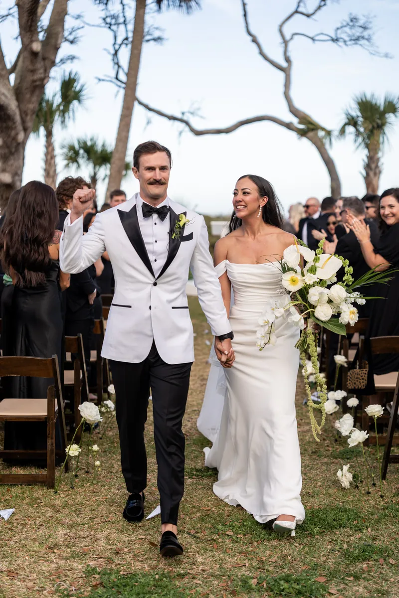 Groom fist pumping while walking down the aisle with bride during recessional