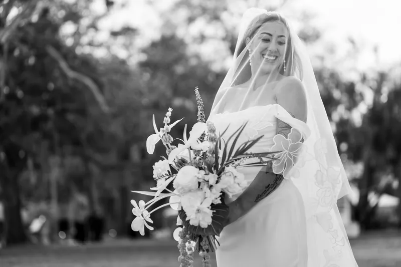 Black and white portrait of bride smiling under her veil with bouquet