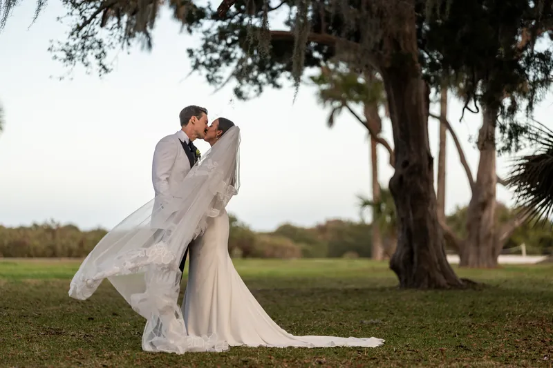 Romantic dip kiss under the live oaks at Fountain of Youth with veil flowing