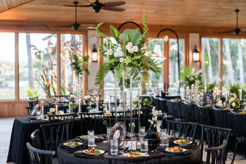 Wide reception room setup with tropical centerpieces and black tablecloths in Magnolia Room